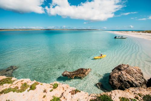 Two people on kayaks paddling on clear blue water at Dirk Hartog Island National Park