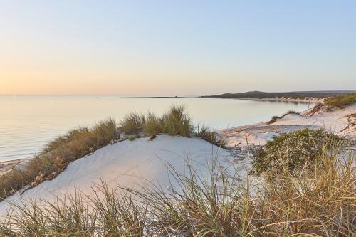 View of bay with white coastal dunes and millpond ocean at sunset