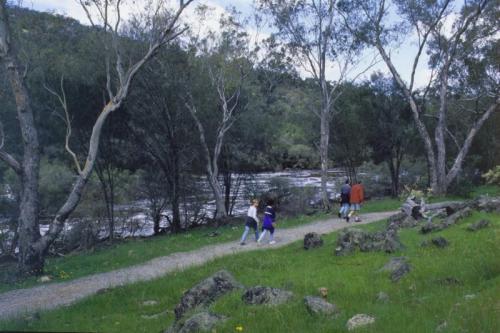 People walking on trail near a river. 
