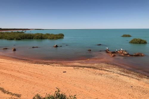 Red sand beach with blue waters.