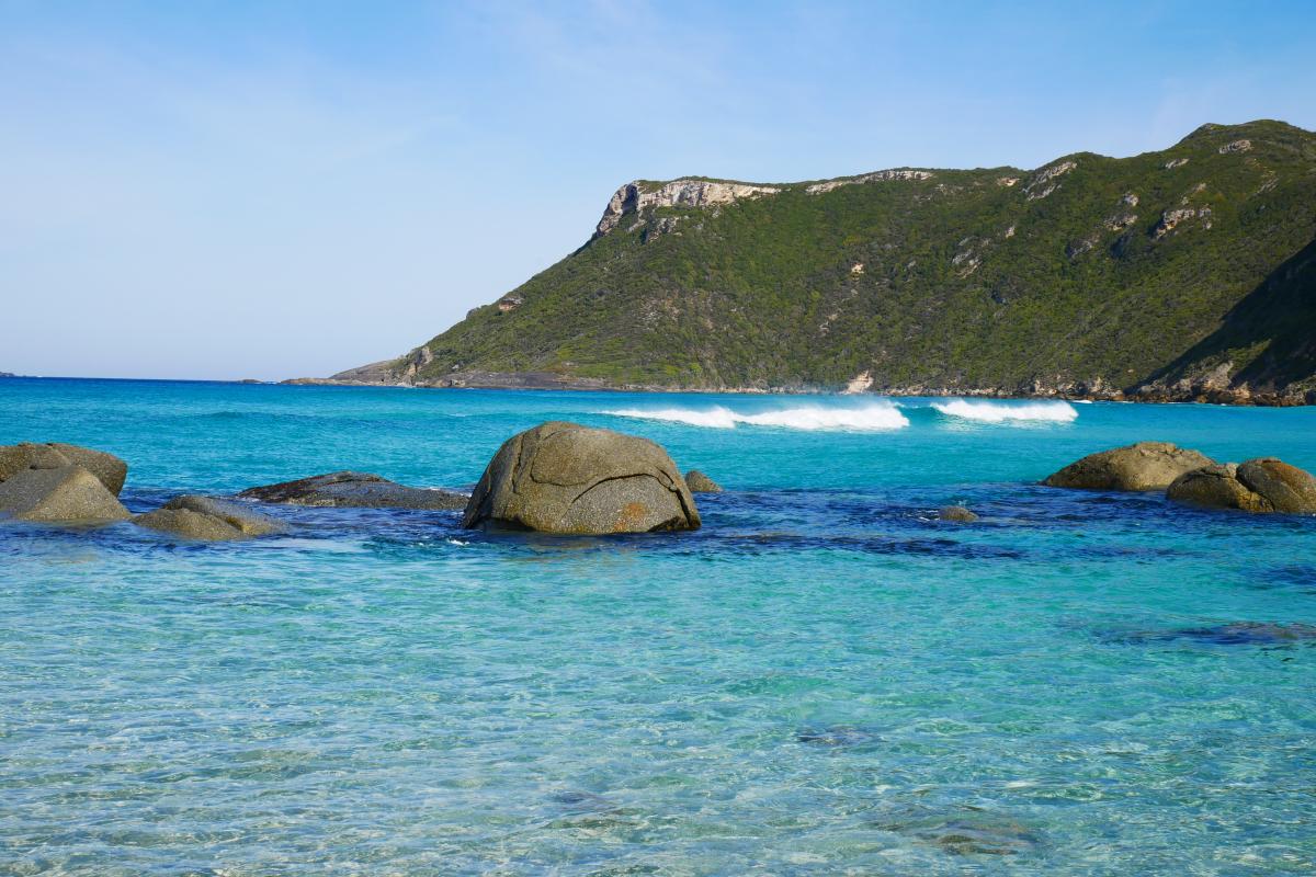 clear blue water with granite boulders and headland off in the distance